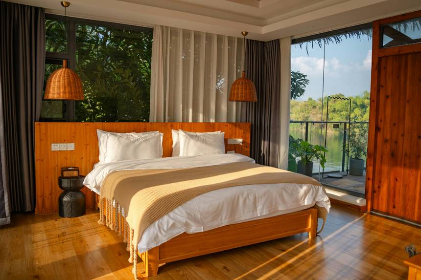Quarto de pousada arrumado, com luz de fim de tarde e vista para a mata